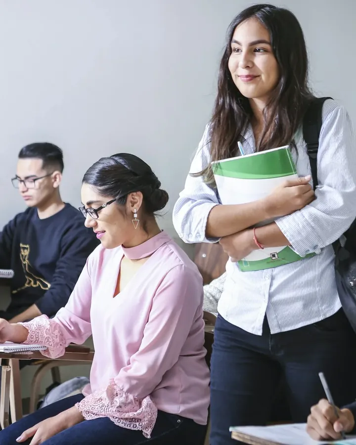 Étudiants en salle de cours, une étudiante debout tient ses classeurs