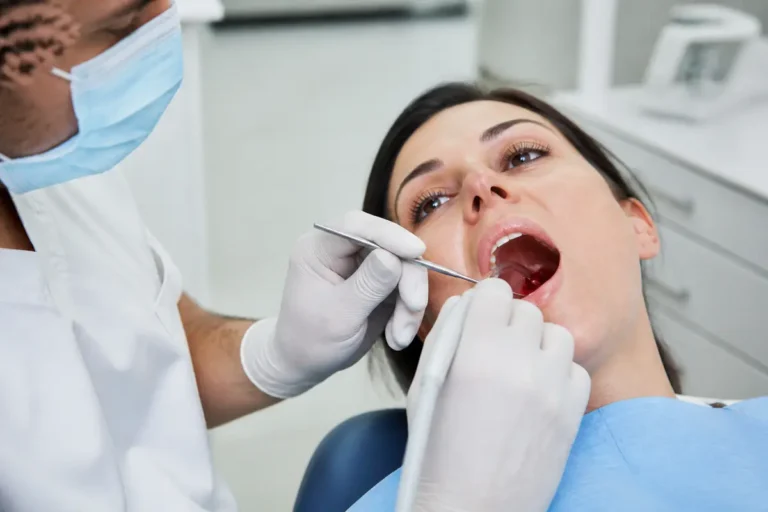 Dentiste examinant une patiente, portant des gants et masque, dans un cabinet médical lumineux.