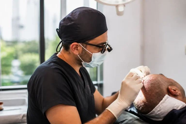 Chirurgien effectuant une greffe capillaire sur un patient, portant masque et gants, dans une clinique bien éclairée.